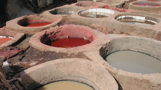 Traditional stone vats filled with colored dyes in a tannery, showcasing the leather dyeing process used in handmade leather production.