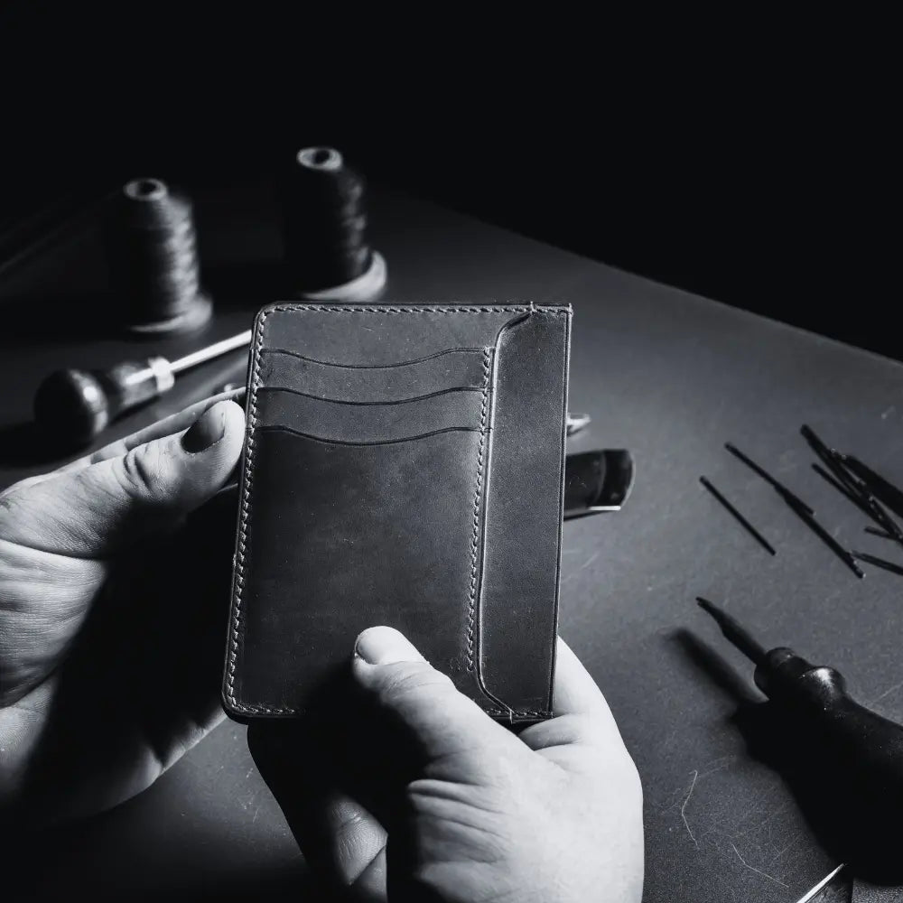 Artisan holding a handmade leather wallet with detailed stitching, showcasing the craftsmanship and quality of leather accessory creation.